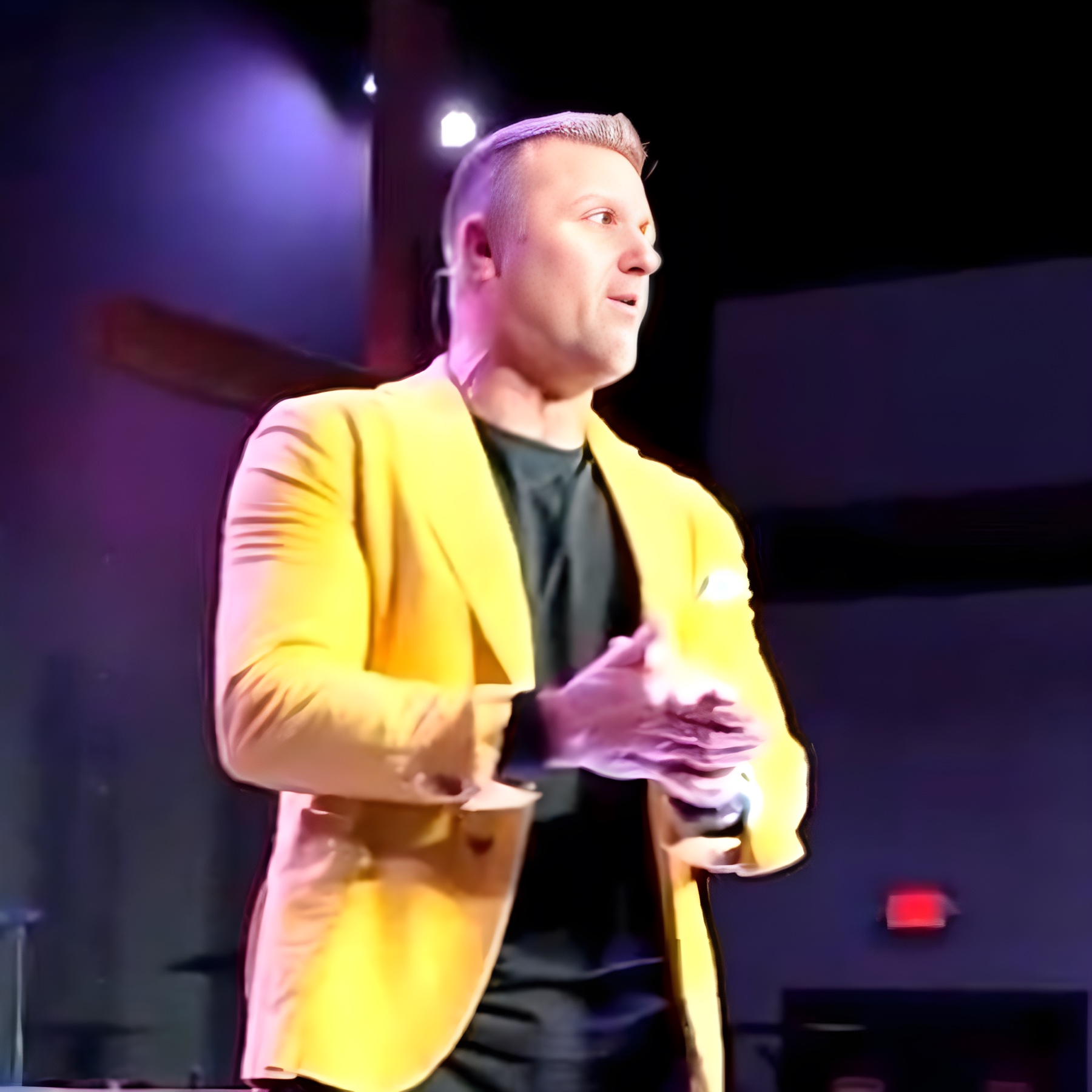 Jeremy on stage in a yellow blazer, mid-keynote
